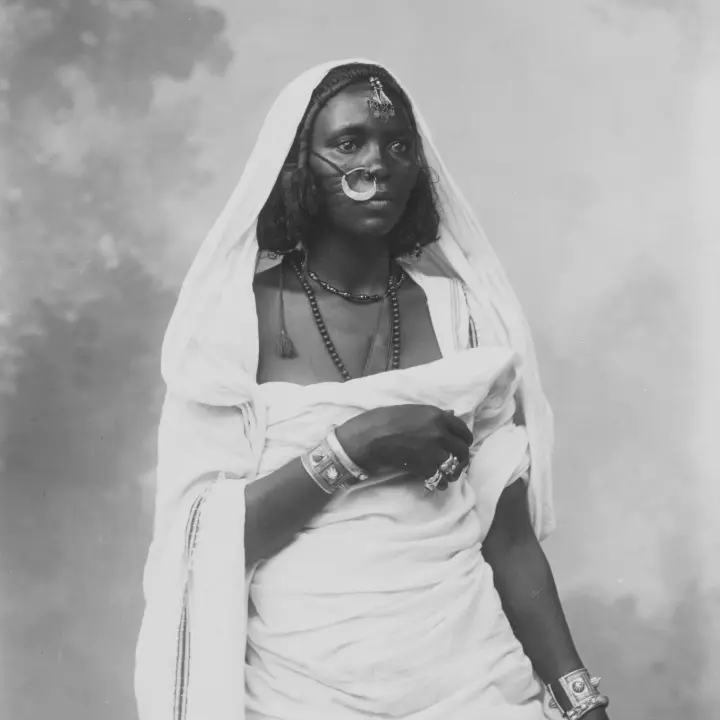 Ritratto di donna africana in costume tradizionale, con gioielli decorativi.